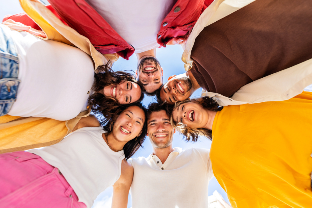 Groupe de 6 amis regardant l'objectif vers le sol et souriant toutes et tous.